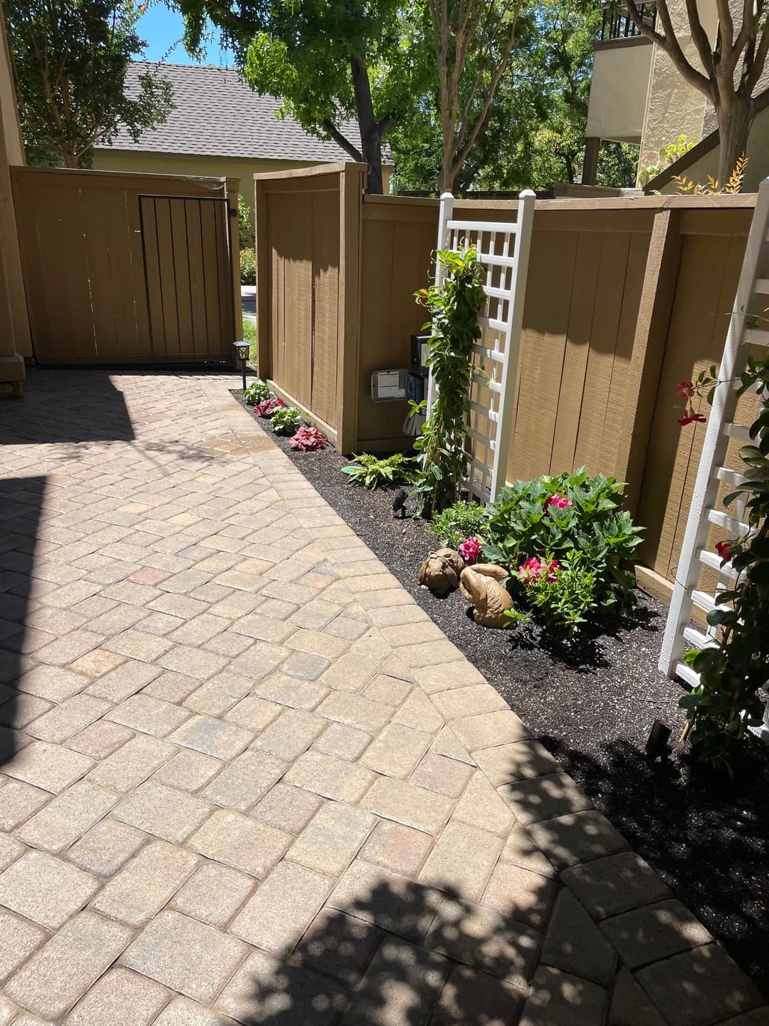 garden pathway with flower beds and decorative fencing in a sunny outdoor area