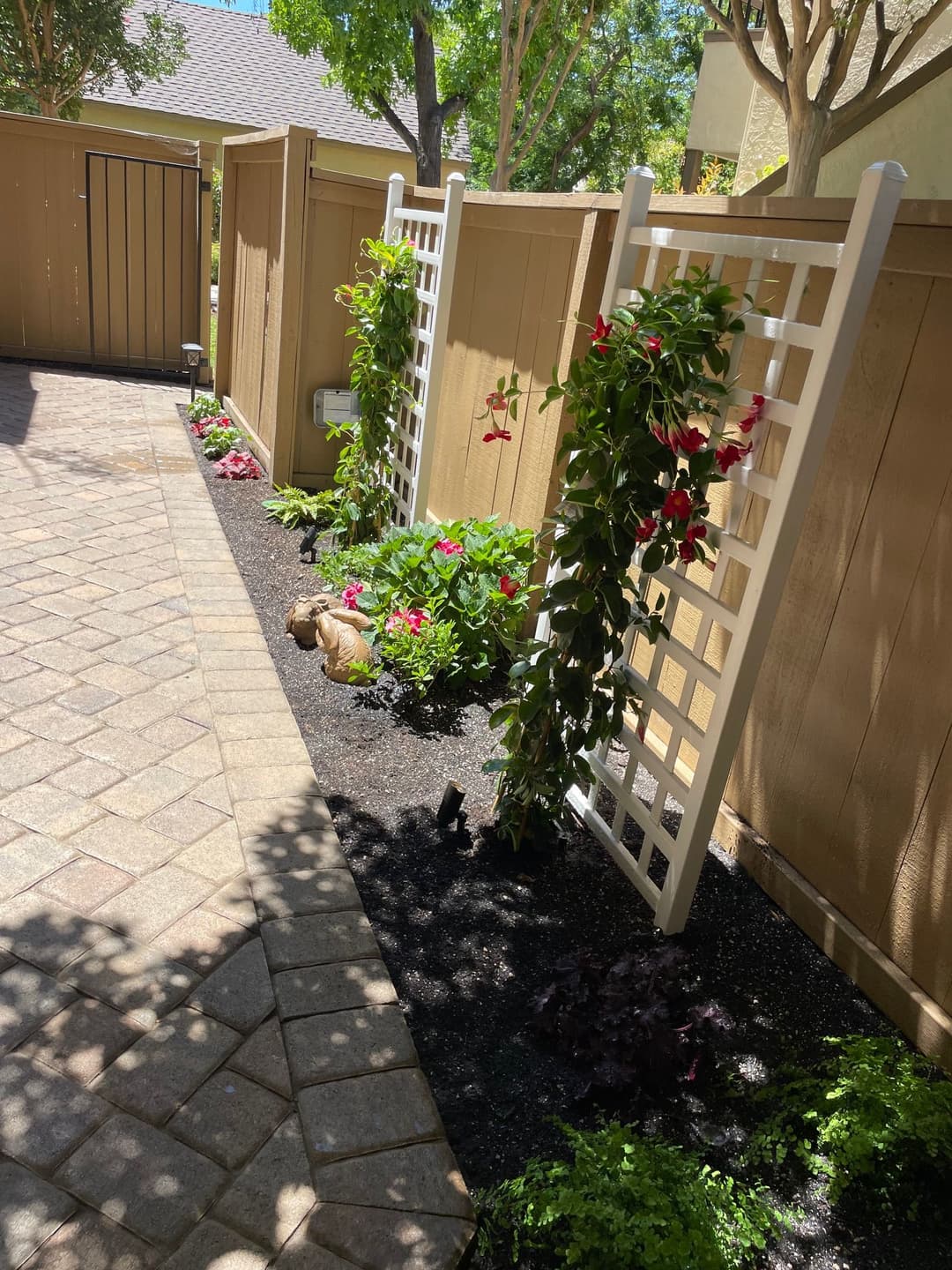 White lattice trellis with climbing flowers in a landscaped garden pathway.