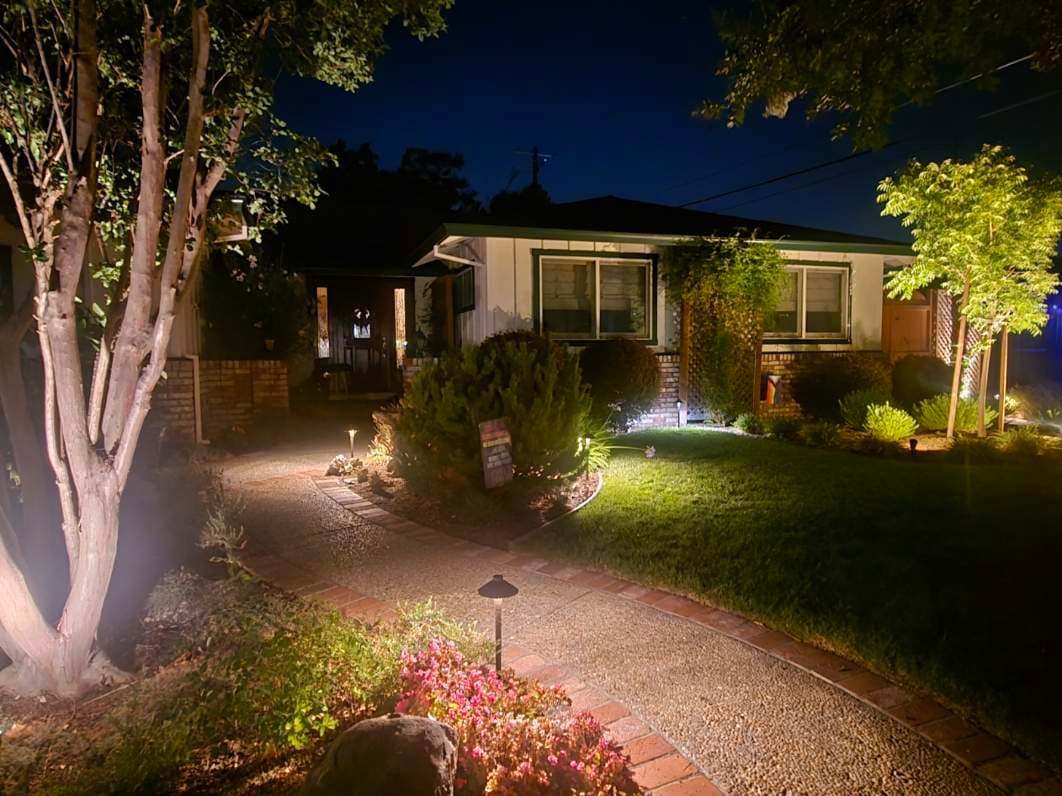 Charming night view of a well-lit suburban home with landscaped garden pathway.
