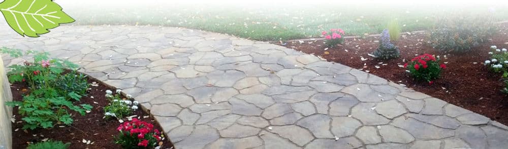 Curved stone pathway bordered by colorful flowers and lush green grass.