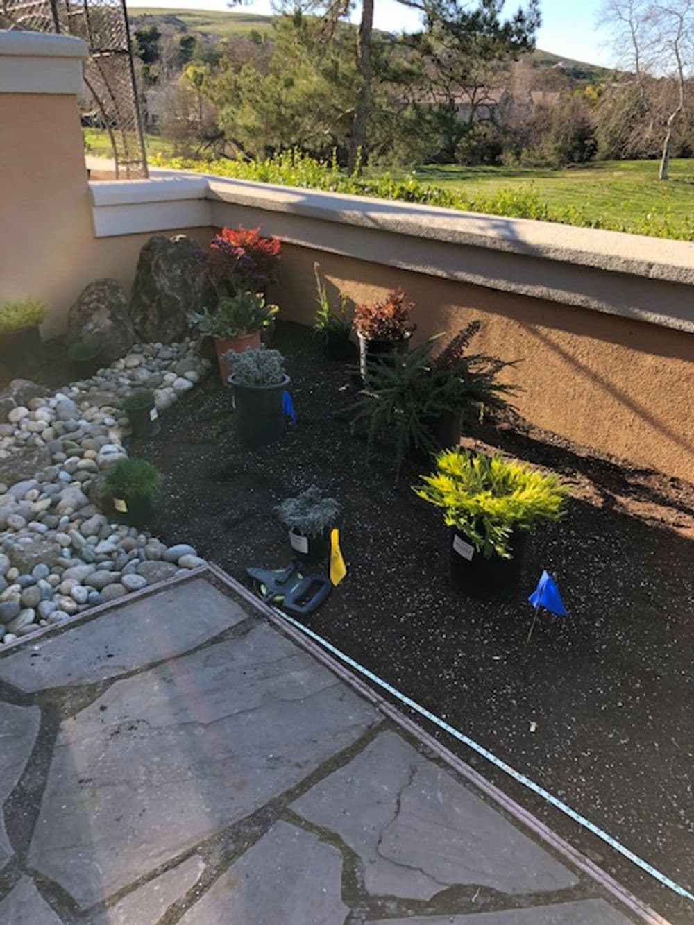 Garden landscape with potted plants and colorful flags, sunlight enhancing natural beauty.